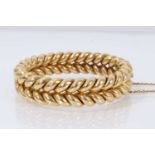 Victorian yellow metal hinged bangle with a double rope twist design, stamped '18ct' to the clasp.
