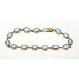 Blue topaz and gold bracelet with 14 oval mixed cut blue topaz in 9ct gold setting, 19.5cm.