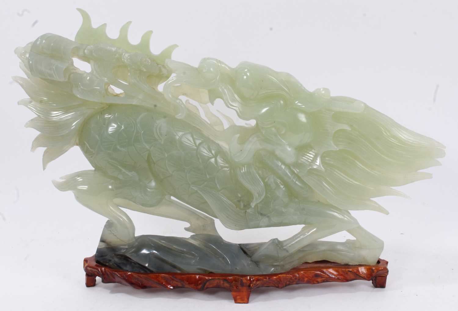 Large Chinese jade or green hardstone carving of a mythical beast, raised on wooden plinth, 43cm lon