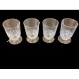 Set of four 1930s Lalique 'Pouilly' liqueur glasses with moulded fish band against a frosted blue gr