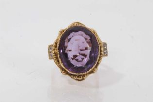 Amethyst and diamond ring with a large oval mixed cut amethyst in gold setting, diamond set shoulder