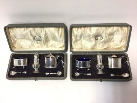 A pair of three piece condiment sets, comprising salt, pepper and mustard with matching spoons,