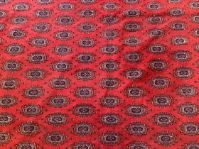 Large Bokhara carpet with thirteen rows of twenty-nine medallions on blood red ground with multiple