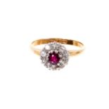 Antique ruby and diamond cluster ring with a central mixed cut ruby surrounded by nine old cut diamo