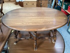 Ercol elm oval drop leaf coffee table on turned and block legs joined by stretchers