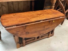 Hardwood oval drop leaf table on turned and block legs joined by stretchers