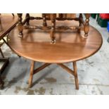 Ercol elm oval drop leaf table on square legs joined by x frame stretchers, opening to 112cm x 124cm