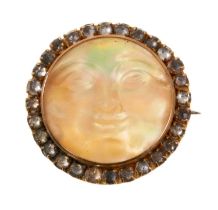 Antique carved mother of pearl brooch in the form of the man on the moon, surrounded by a border of