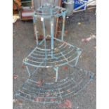 A wrought iron three tier plant stand of slatted form