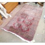 An Afghan hand made wool rug with repeat gul motifs within a wide triple border on red ground - half