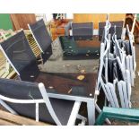 A large metal framed garden table with black glass top and twelve matching chairs