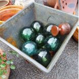 A large garden planter containing a quantity of glass fishing floats