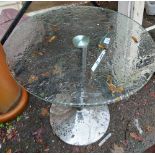 A retro glass topped circular table, set on chrome pillar and tapered base