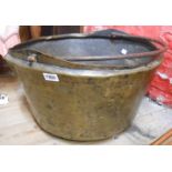A large antique brass cooking pot with wrought iron handle