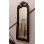 An Edwardian walnut framed narrow wall mirror with arched bevelled plate and pierced decoration to