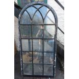 A large window of arched form with painted cast iron frame