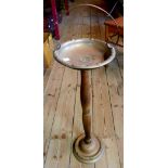 A vintage brass ashtray set on turned wooden column with loop handle