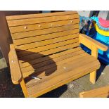 A modern two seater wooden garden bench of slatted form