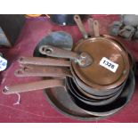 A quantity of antique copper saucepans and associated lids, etc.