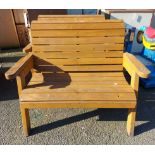 A modern two seater wooden garden bench of slatted form