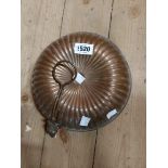 An old copper hot water bottle/bed warmer of ribbed cushion form with holding handle