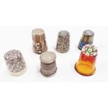 A selection of silver and other thimbles comprising three hallmarked silver (one with glass top),