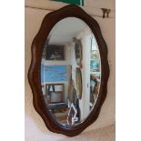 A vintage oak framed bevelled oval wall mirror with serpentine outline