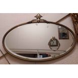 A vintage brass framed bevelled oval wall mirror with shaped pediment