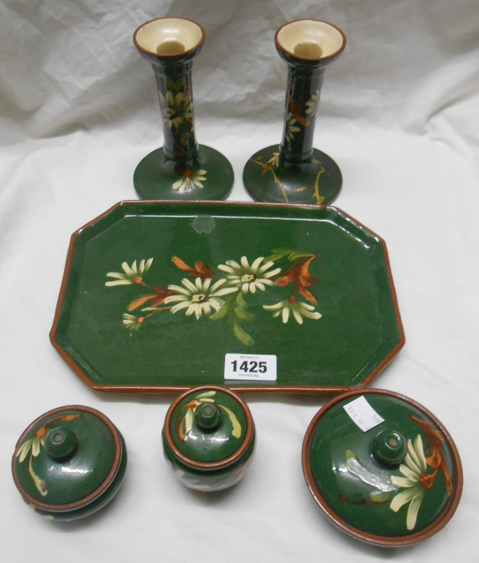 A Watcombe Torquay dressing table set comprising pair of candlesticks and three lidded pots on a