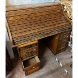 A 1.25m vintage stained oak roll-top desk with part fitted interior and flanking pedestal slides,