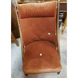 An early 20th Century stained beech framed folding chair with russet velour upholstery