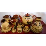 A selection of Torquay pottery motto ware items including shaving mugs, match striker, teapots, etc.