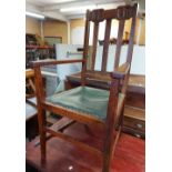 A pair of early 20th Century oak framed lathe back elbow chairs with carved floral decoration to top