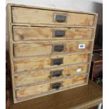 A vintage six drawer collector's chest with stripped finish and metal handles