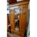 A 95cm early 20th Century oak single wardrobe with hanging space enclosed by a bevelled mirror panel