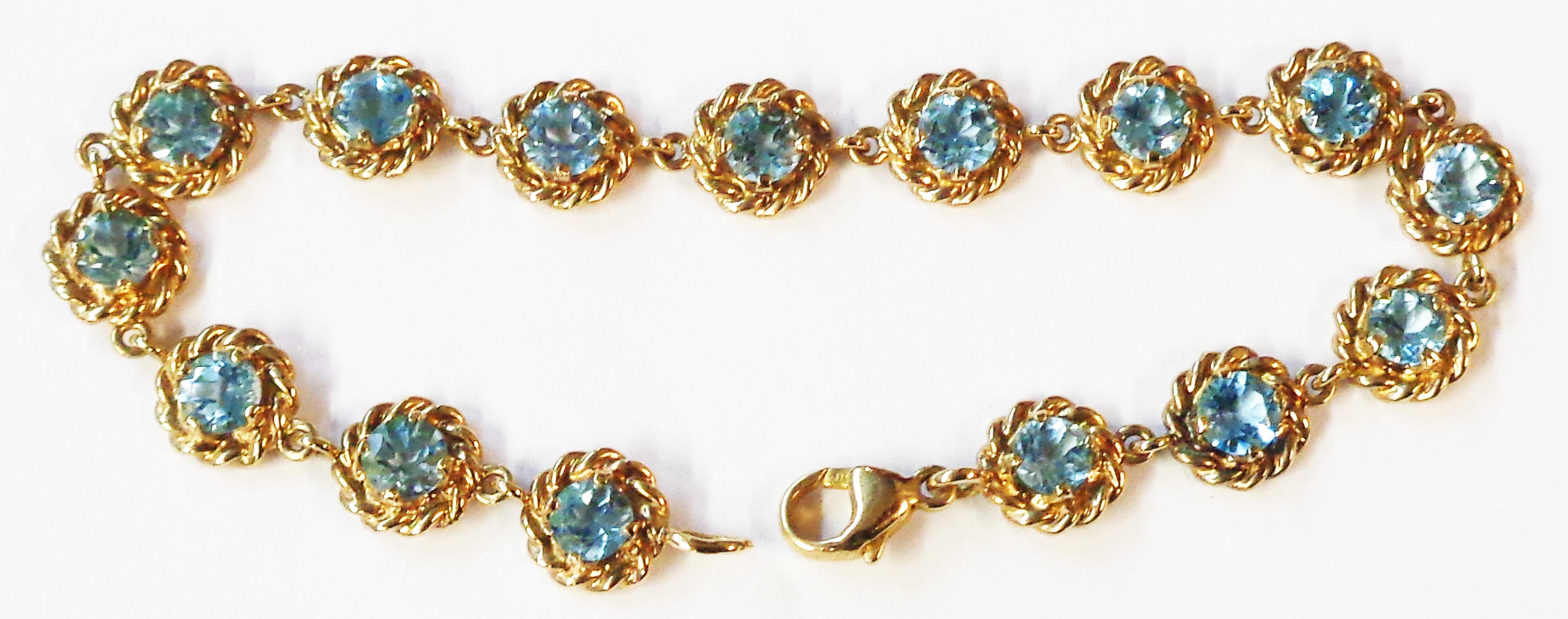 A 375 (9ct.) gold bracelet, set with fifteen blue topaz stones within rope-twist bordered circular