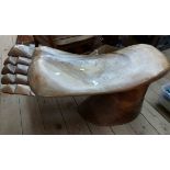 A 90cm carved polished hardwood low stool in the shape of an upturned human foot, set on a rustic