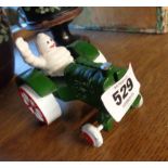 A modern painted cast iron model of the Michelin Man driving a tractor