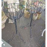 A pair of black painted metal freestanding flower baskets with scroll decoration