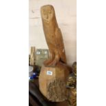 A large carved wood figurine depicting an owl seated on a trunk