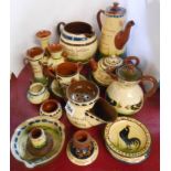 A quantity of Torquay pottery motto ware including match strikers, shaving mug, tyg, coffee pot,