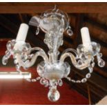 A three branch glass electric chandelier with cut glass lustre drops and sconces