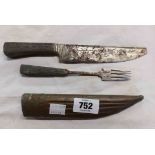 An Eastern knife and fork carving set with decorative chased blade and pewter handles, set in