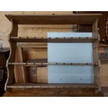 A 1.33m old stripped pine wall mounted three shelf open plate rack with numerous cup hooks