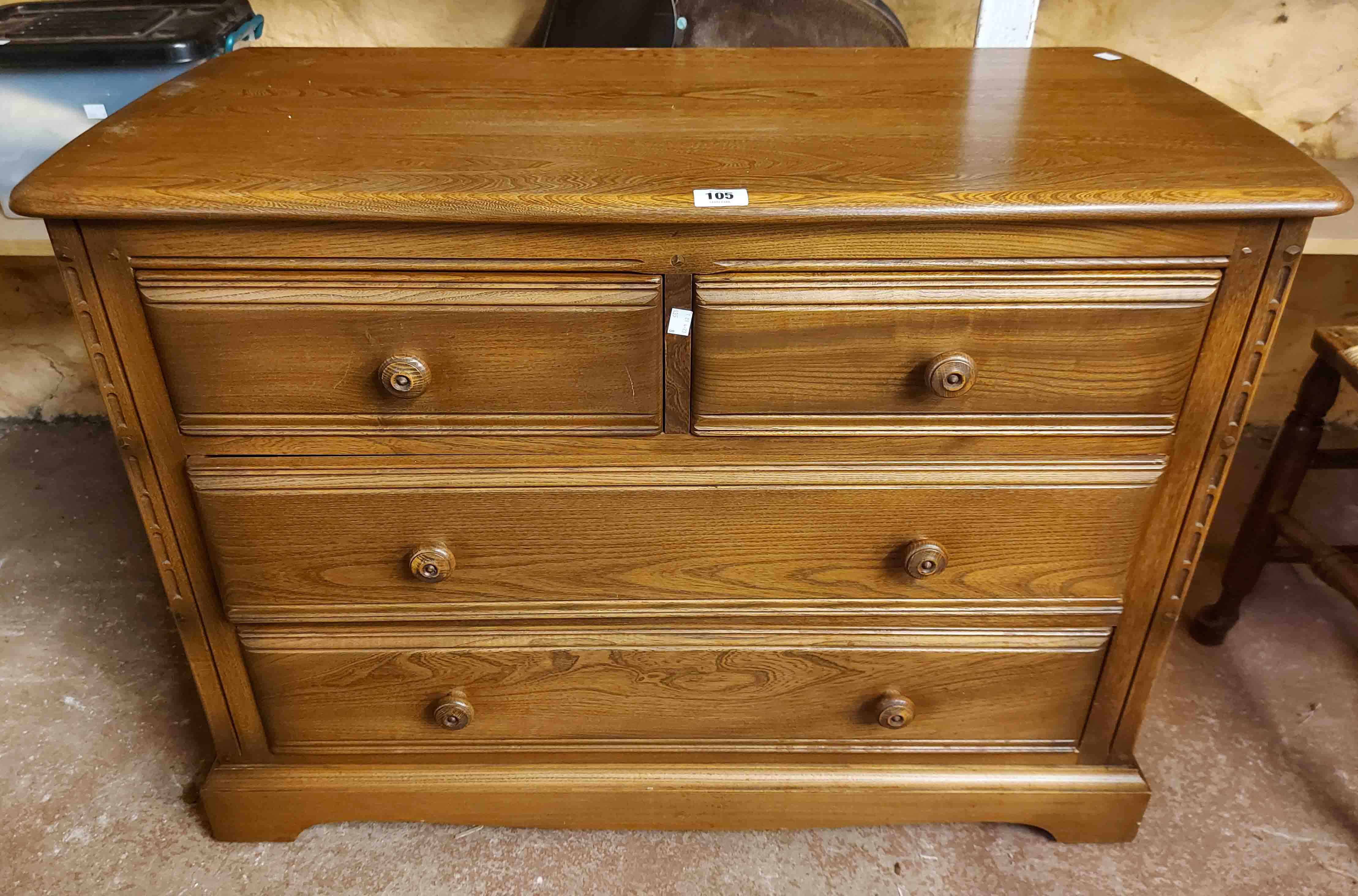 A 98cm Ercol stained elm chest of two short and two long drawers, set on bracket base