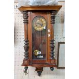 An early 20th Century stained walnut cased Vienna style wall clock with visible pendulum and