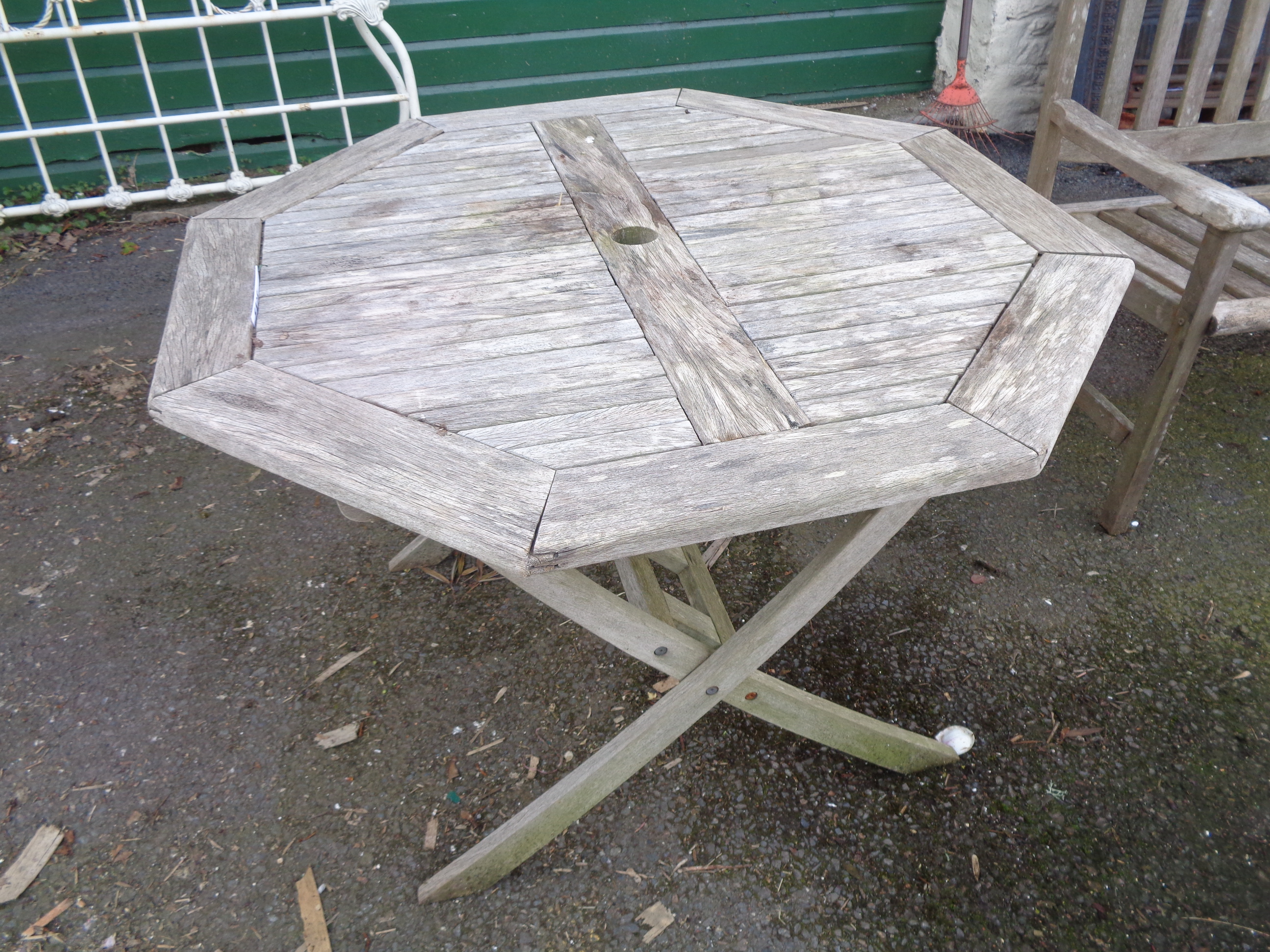 A teak garden table of octagonal slatted form