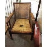 A 19th Century mahogany bergere elbow chair with padded leather arms and swab cushion, set on