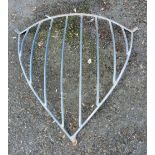 A vintage metal hay rack of curved form