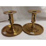 A pair of brass ejector candlesticks with wide drip tray bases